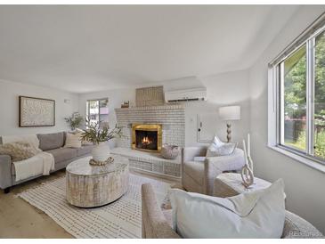 Bright living room featuring a brick fireplace, plush seating, and natural light at 1018 Kelly Pl, Longmont, CO 80501