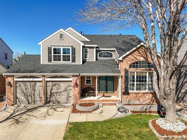 Charming two-story home with a brick and gray exterior, two-car garage, and a well-manicured front yard at 10055 Hughes Pl, Highlands Ranch, CO 80126