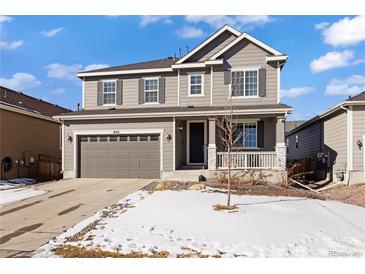 Two-story house with gray siding, a three-car garage, and a partially snow-covered front yard at 6211 Leilani Ln, Castle Rock, CO 80108