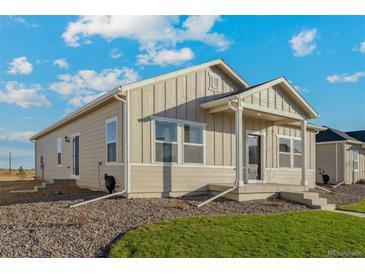 Inviting single story home with neutral siding, manicured front lawn, and lovely covered front porch and entryway at 2997 Pershing St, Strasburg, CO 80136