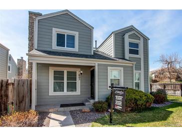 Charming two-story home with light grey siding, a stone chimney, and a well-maintained front yard under a clear blue sky at 11605 E Cornell Cir, Aurora, CO 80014