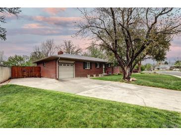Charming brick home featuring an attached garage and large front yard with mature trees and a long driveway at 6365 S Valleyview St, Littleton, CO 80120