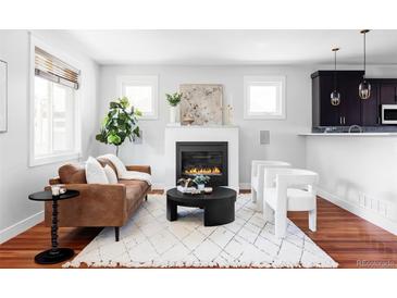Cozy living room features a fireplace, a brown leather sofa, and two white armchairs at 2931 W 20Th Ave, Denver, CO 80211
