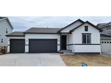 Modern home with a white exterior, dark trim, two-car garage, and a well-maintained front yard at 14390 Heritage Dr, Mead, CO 80504