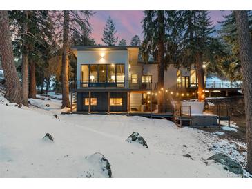 Modern home with a deck, hot tub, and surrounded by trees, set against a snowy landscape and twilight sky at 1290 S Lininger Dr, Golden, CO 80401