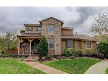 Charming stone home with a well-manicured lawn and inviting front porch with a wood-supported roof at 9592 Firenze Way, Highlands Ranch, CO 80126