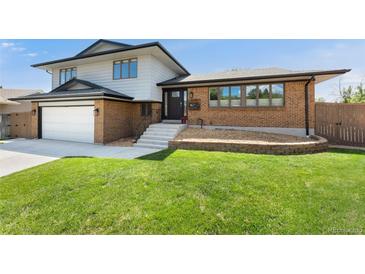 Inviting two-story home featuring a brick facade, well-manicured lawn, and attached two-car garage at 13390 W Warren Ave, Lakewood, CO 80228