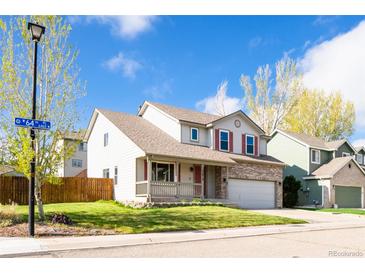 Charming two-story home with a well-maintained lawn and inviting front porch at 13812 W 64Th Pl, Arvada, CO 80004