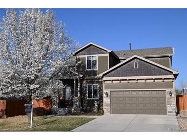 Charming two-story home with a well-manicured lawn, blooming tree, and a two-car garage at 9121 Harlequin Cir, Frederick, CO 80504