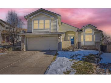 Two-story house with a beige exterior, attached garage, and snowy front yard at 6454 S Swadley Way, Littleton, CO 80127