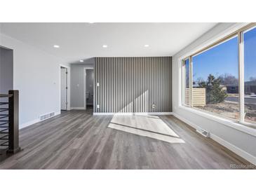 Bright living room features updated gray wood flooring, a large window and a designer gray accent wall at 951 E 10Th Ave, Broomfield, CO 80020