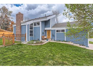 Inviting home featuring a charming front yard, brick chimney, and attractive light-blue siding at 10743 W Berry Pl, Littleton, CO 80127