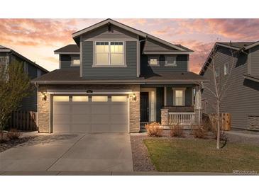 Charming two-story home featuring stone accents, gray siding, a two-car garage, and a well-manicured front yard at 455 N Old Hammer St, Aurora, CO 80018