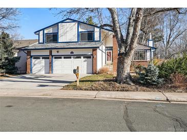 Charming two-story home featuring a three-car garage, blue trim, brick accents, and mature trees in a well-maintained neighborhood at 15974 E Loyola Dr, Aurora, CO 80013