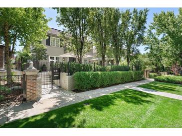 Charming two-story home with manicured lawn, brick entryway, black metal fence, and privacy hedge at 450 Steele St, Denver, CO 80206