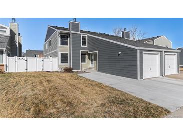 Charming townhome with gray siding, a well-manicured lawn, and an attached two-car garage at 11917 Monroe St, Thornton, CO 80233