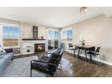 Cozy living room with a fireplace and large windows offering panoramic views and a dining area at 2179 Sunridge Cir, Broomfield, CO 80020