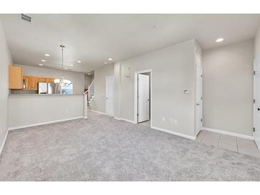 Bright living room with neutral carpet, white walls, and a view into the kitchen with stainless steel appliances at 1401 W 85Th Ave # F201, Federal Heights, CO 80260