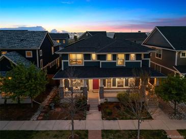 Stunning two-story home showcasing a charming front porch and manicured landscaping, perfect for outdoor relaxation at 9446 E 51St Dr, Denver, CO 80238