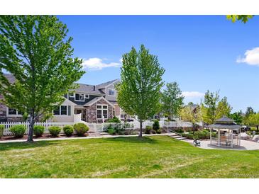 Charming townhouse with a white picket fence, lush lawn, mature trees, and a gazebo in the common area at 14247 Pikeminnow Pl, Broomfield, CO 80023