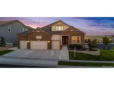 Two-story house with stone and beige siding, three-car garage, and landscaped yard at 15994 La Plata Peak Pl, Broomfield, CO 80023