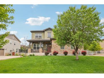 Charming two-story home with a lush green lawn, stone accents, and a welcoming front porch at 2605 Gray Wolf Loop, Broomfield, CO 80023