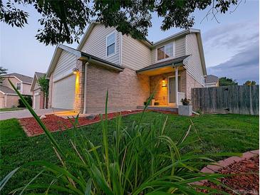 Two story home with tan siding, brick accents, and a well-maintained lawn and landscaping at 3982 S Himalaya Way, Aurora, CO 80013