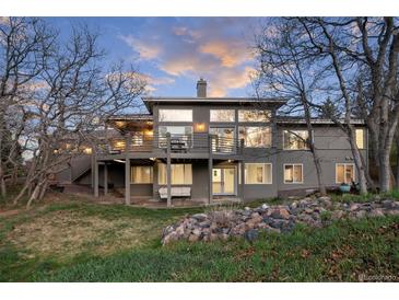 A modern home with a large deck and patio is surrounded by beautiful landscaping and mature trees at 5631 Silver Bluff Ct, Parker, CO 80134