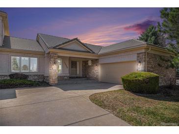 Charming stucco home featuring a tiled roof, stone accents, covered entryway, and attached garage at 13806 E Chenango Dr, Aurora, CO 80015