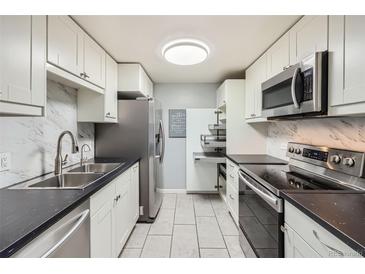 A modern kitchen with white cabinetry, stainless steel appliances, and sleek black countertops at 4940 E Donald Ave # 8, Denver, CO 80222