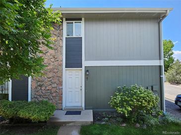 View of home with a stone accent wall and a white front door surrounded by green shrubbery and grass at 10001 E Evans Ave # D, Aurora, CO 80247