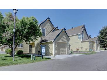 View of a tan two-story home with a two-car garage and a well-manicured lawn on a sunny day at 10359 W Fair Ave # F, Littleton, CO 80127