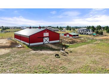 Bright red barn with a white accent, paddocks and horses creates a true country feel at 2190 Helen Ct, Parker, CO 80138