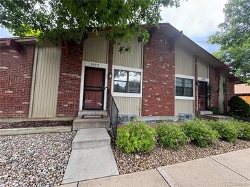 Red brick townhome featuring a secure screen door and well-kept front yard with decorative rock at 7020 W Portland Ave, Littleton, CO 80128