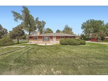 Charming single-story home with a well-manicured lawn and mature trees under a clear blue sky at 14505 W 52Nd Ave, Arvada, CO 80002