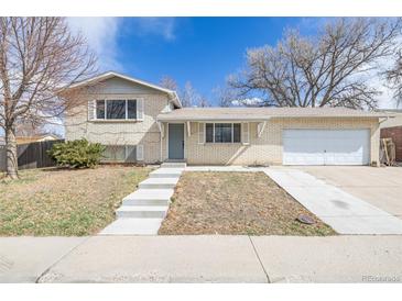 Charming exterior of this home showcasing a well-maintained yard, brick facade, driveway, and attached two-car garage at 5542 Sable St, Denver, CO 80239