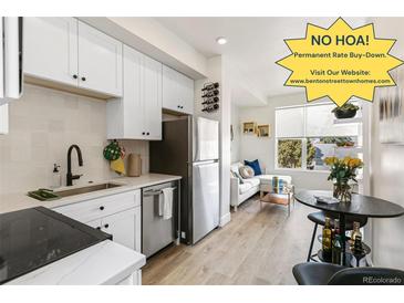 Bright kitchen featuring white cabinets, stainless steel appliances, and modern finishes open to living area at 5371 W 14Th Ave, Lakewood, CO 80214