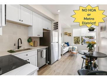 Modern kitchen with stainless appliances, white cabinets, stylish backsplash, and a view to the cozy living area at 5371 W 14Th Ave, Lakewood, CO 80214