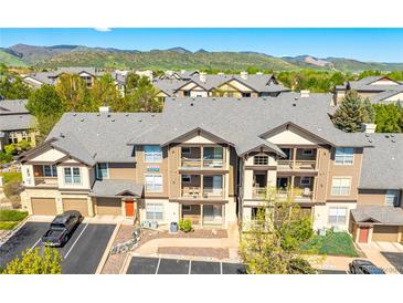 Inviting condo building featuring a gray roof, beige siding, balconies, and well-kept landscaping at 7433 S Quail Cir # 1924, Littleton, CO 80127