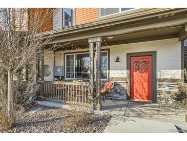 Charming front porch with a red door, decorative wreath, and cozy seating area, perfect for relaxing outdoors at 21613 E 59Th Pl, Aurora, CO 80019