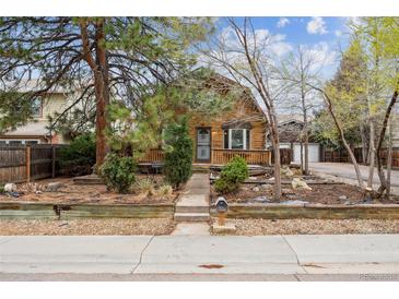 Charming log cabin-style home with a cozy front porch and well-maintained landscaping at 8409 S Otis St, Littleton, CO 80128