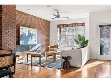 Modern living room featuring exposed brick wall, stylish furniture, and hardwood floors, bathed in natural light at 425 S Reed St, Lakewood, CO 80226