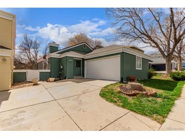Charming green home featuring an attached two-car garage and well-maintained front yard with mature tree at 2675 S Deframe Cir, Lakewood, CO 80228