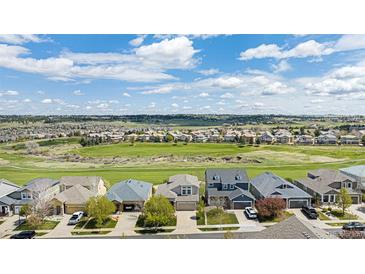 An aerial view of a residential area with lush golf course and mountain views on a sunny, cloudy day at 11788 Mill Valley St, Parker, CO 80138