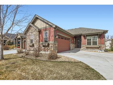 Charming exterior view of a home featuring a two-car garage, stone accents, and a well-manicured lawn at 4533 Angelina Cir, Longmont, CO 80503