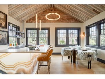 Modern kitchen with a marble island, exposed brick, high ceilings, and large windows at 3309 E 7Th Ave Pkwy, Denver, CO 80206