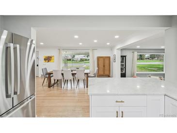 Open concept dining room with hardwood floors, large windows, and stainless steel refrigerator in view at 3285 N Monaco Pkwy, Denver, CO 80207