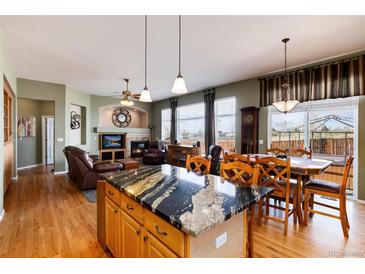 Inviting living room with a black granite kitchen island and a cozy seating area with fireplace at 11302 Mesa Verde Pl, Parker, CO 80138