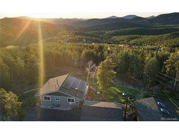 Stunning aerial view of a home nestled in the mountains with solar panels and mature trees at 8 Sioux Trl, Evergreen, CO 80439