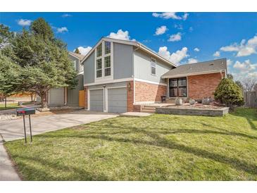 Charming two-story home with a well-manicured lawn, mature tree, and brick accents under a bright, cloudy sky at 11488 E Amherst S Cir, Aurora, CO 80014